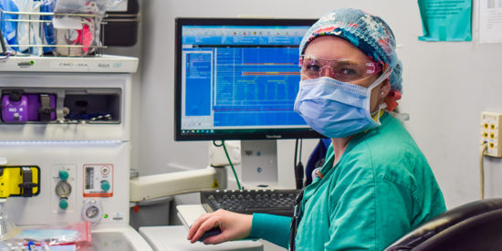 Emily Bludov, a certified registered nurse anesthetist (CRNA), looks up from an anesthesia machine in an operating room at Atrium Health’s Carolina’s Medical Center.
