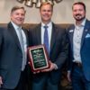 Joel Olsen receives Business Person of the Year award from 2023 LKN Chamber Chair Douglas Marion and Bobby Cashion representing the Cashion family. The award is named for the late Robert T. Cashion. Photo: John McHugh / Ocaid Photography